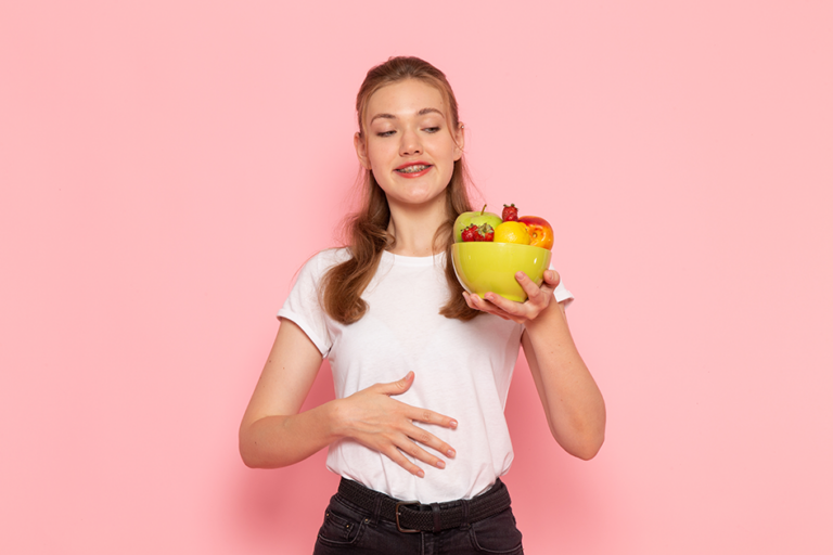 young female holding plate with fresh fruits