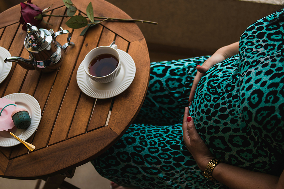 Pregnant woman drinking tea while managing morning sickness naturally