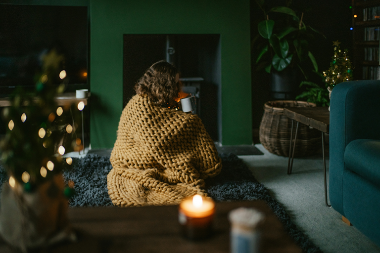 Woman relaxing in a calm evening setting with tea and soft lighting