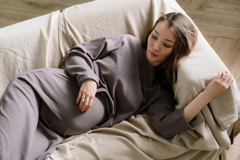 Pregnant woman resting comfortably at home while experiencing pregnancy fatigue