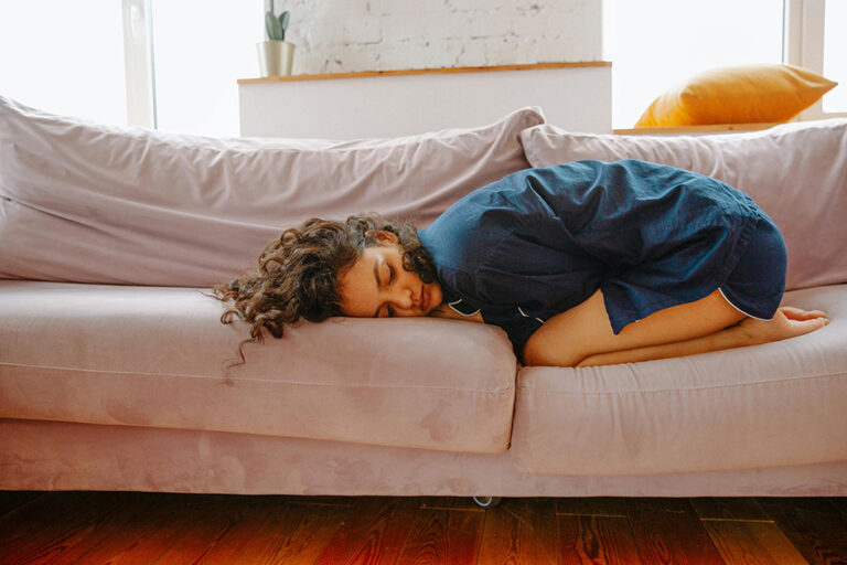 Woman resting on sofa before her period due to hormonal fatigue