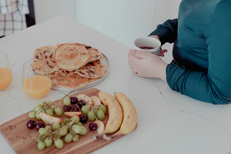 Woman sitting with healthy breakfast and tea, representing gut health and natural energy support