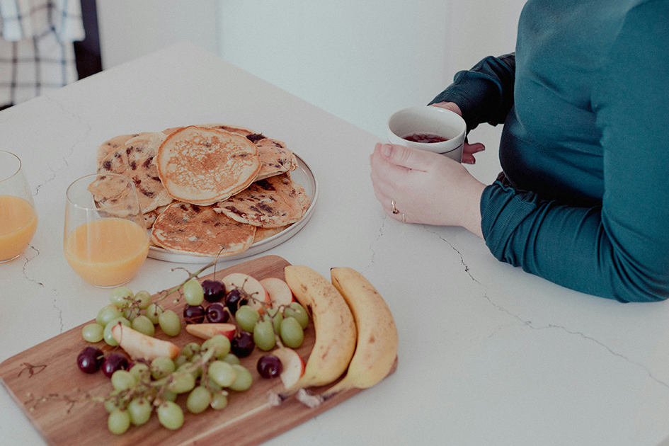 Woman sitting with healthy breakfast and tea, representing gut health and natural energy support