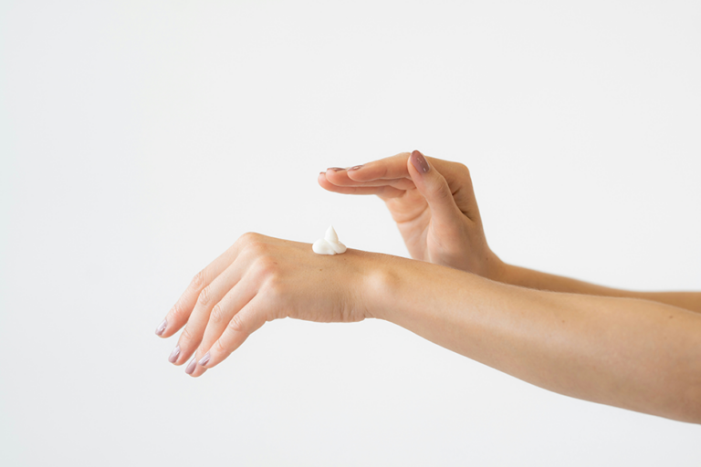 Woman applying moisturizer to her hand as part of a daily skincare routine