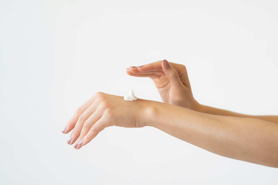 Woman applying moisturizer to her hand as part of a daily skincare routine