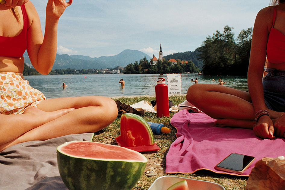 Women enjoying watermelon by a lake on a warm summer day