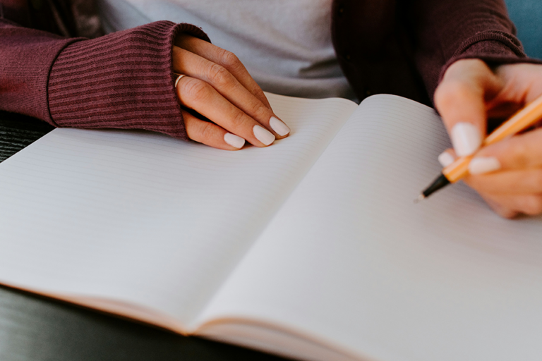 Busy woman journaling in a notebook during a self-care moment to support mental health and emotional wellness