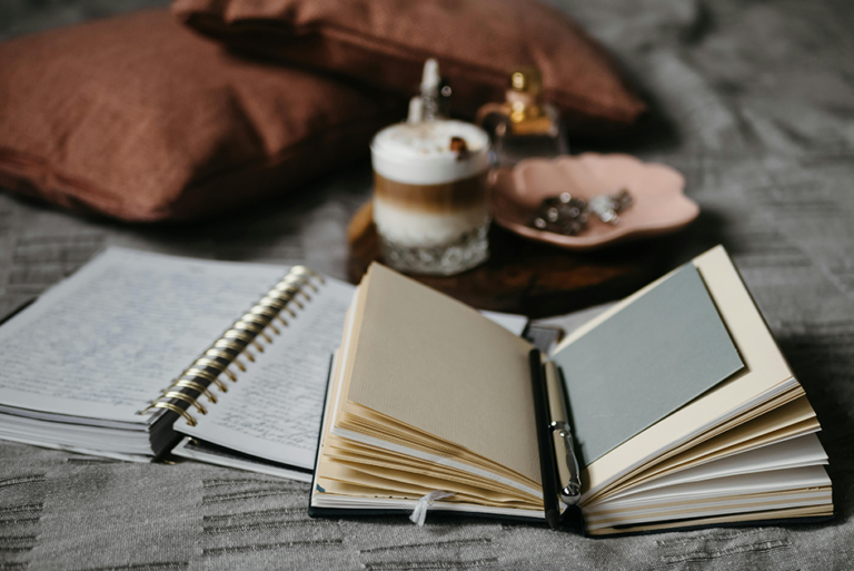 Guided journals, a pen, and a candle arranged in a cozy self-care setting for mental health and stress relief