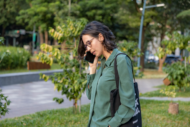 Busy woman walking and talking on her phone outdoors