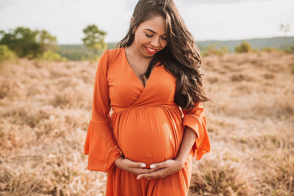 Pregnant woman holding her baby bump and smiling during pregnancy