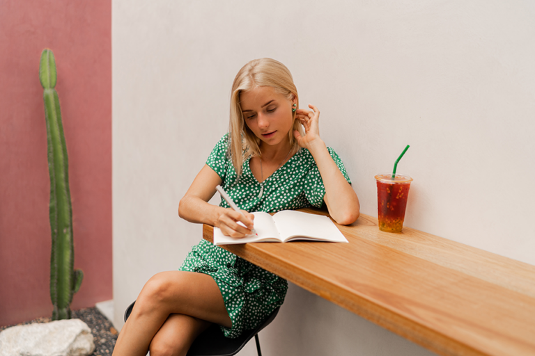 Woman writing in a notebook at a wooden table