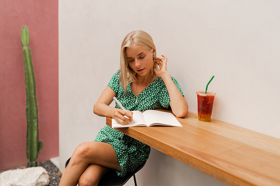 Woman writing in a notebook at a wooden table