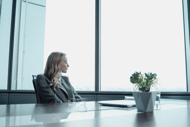Woman taking a quiet pause by an office window to protect her energy