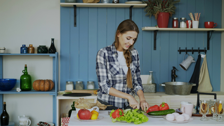 Woman preparing a colorful high-fiber meal with vegetables, chickpeas, avocado, fruit, and whole grains
