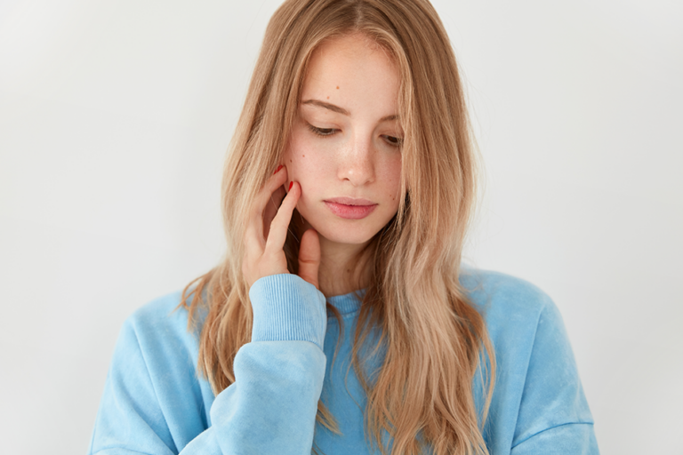 Woman gently touching her face with sensitive skin concerns