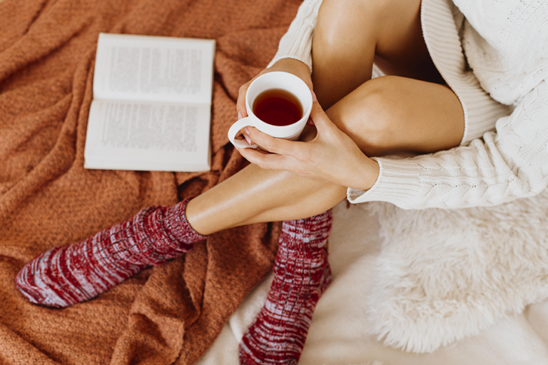 Woman enjoying a quiet self-care moment with tea and a book