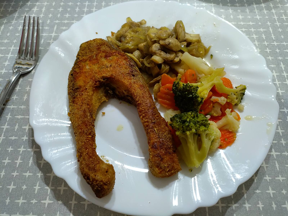 Healthy fish meal with vegetables and mushrooms on a white plate