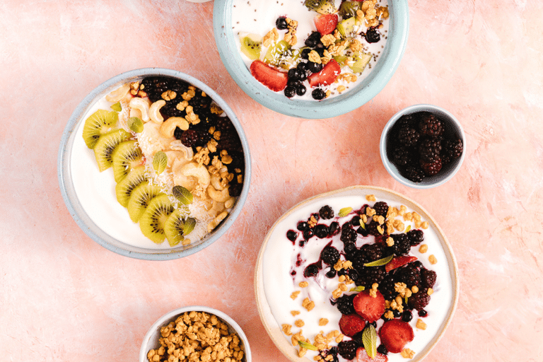Greek yogurt bowls topped with berries, kiwi, granola, and nuts