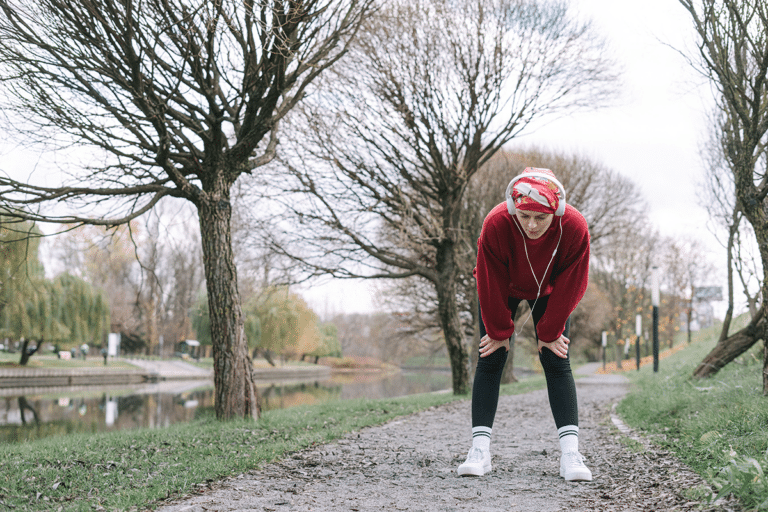 Woman pausing during a walk in the park because her legs feel heavy and tired after exercise