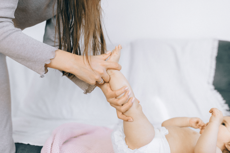 Mother gently caring for her baby's skin during a diaper change at home