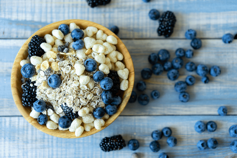 Fresh and frozen blueberries beside a bowl of blueberry baked oatmeal