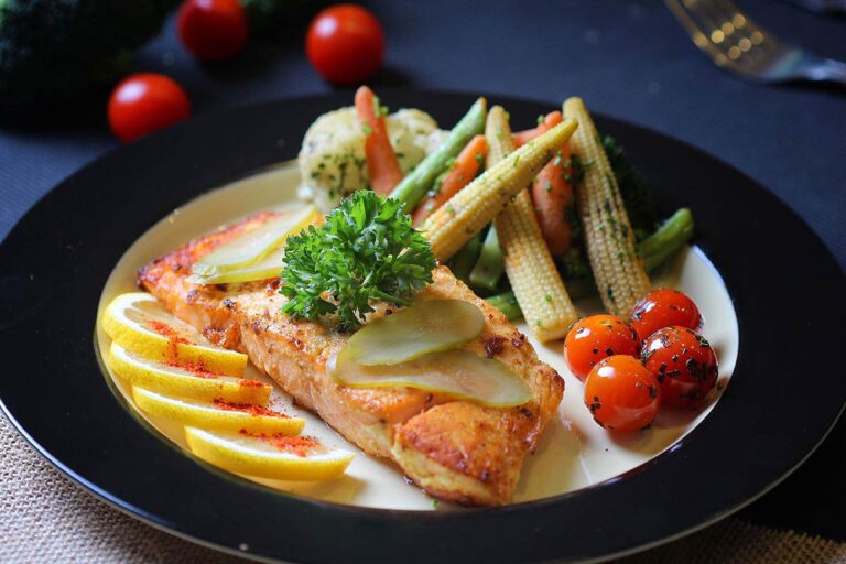 Grilled salmon fillet with lemon, cherry tomatoes, baby corn, and mixed vegetables