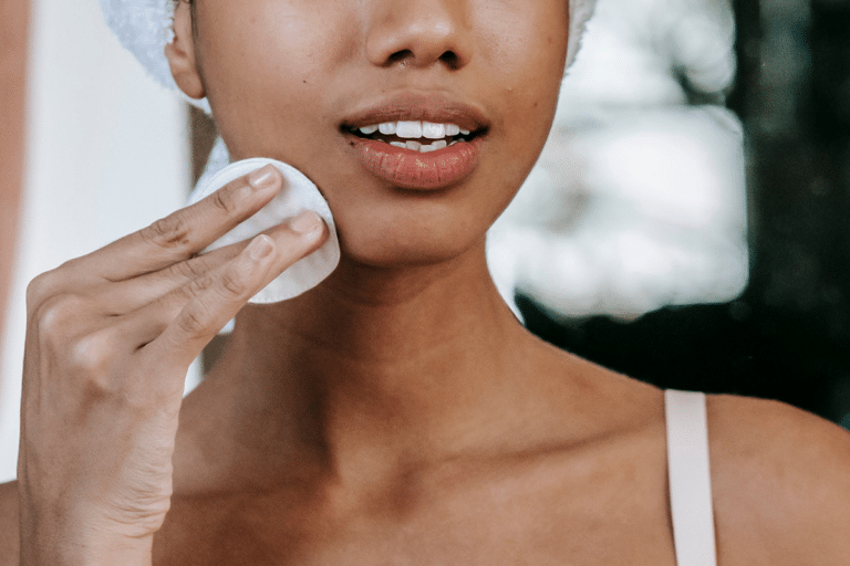Woman gently exfoliating her face with a cotton pad during her evening skincare routine