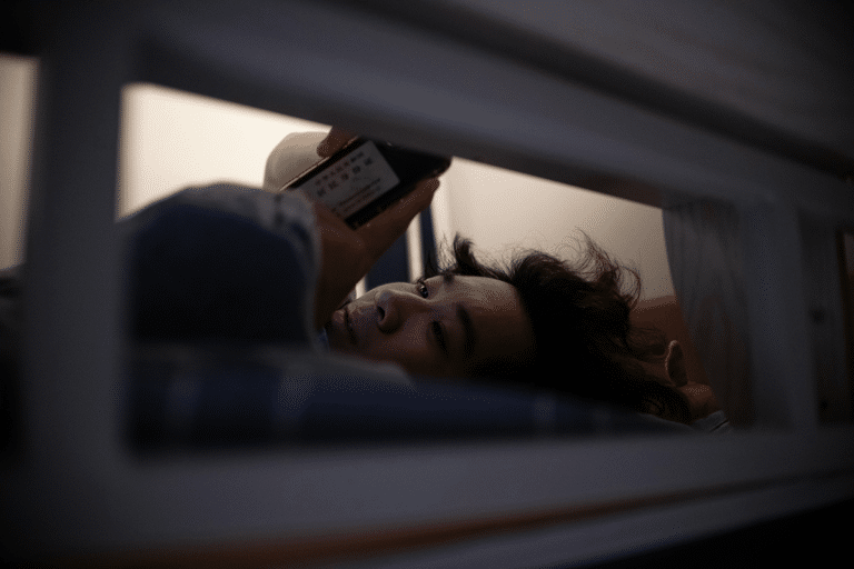 Woman staying up late and scrolling on her phone instead of going to sleep