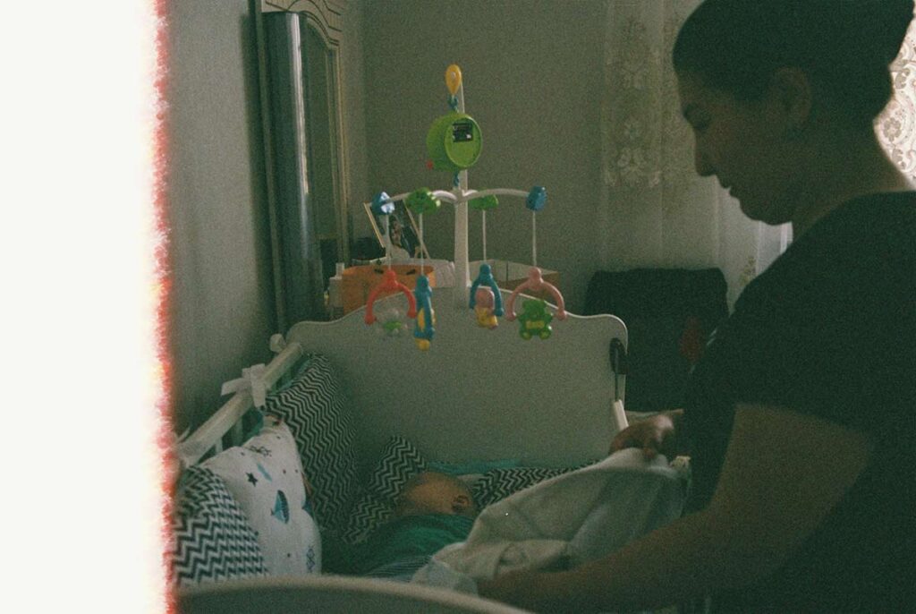 Mother gently placing her sleeping baby into a crib