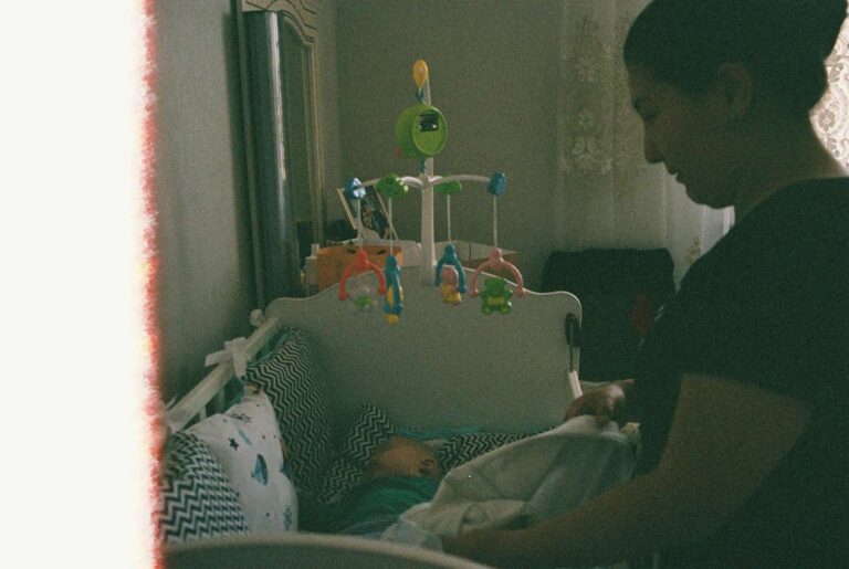 Mother gently placing her sleeping baby into a crib