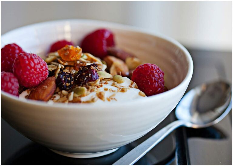 Filling oatmeal bowl with berries, banana, walnuts, and Greek yogurt