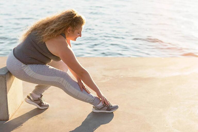Woman stretching her leg by the water, illustrating joint stiffness and aches during perimenopause