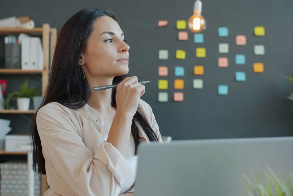 Woman pausing at her desk before starting a task, illustrating perfectionism and procrastination