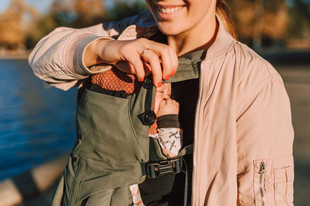 Mother safely carrying her newborn close to her chest in a baby carrier