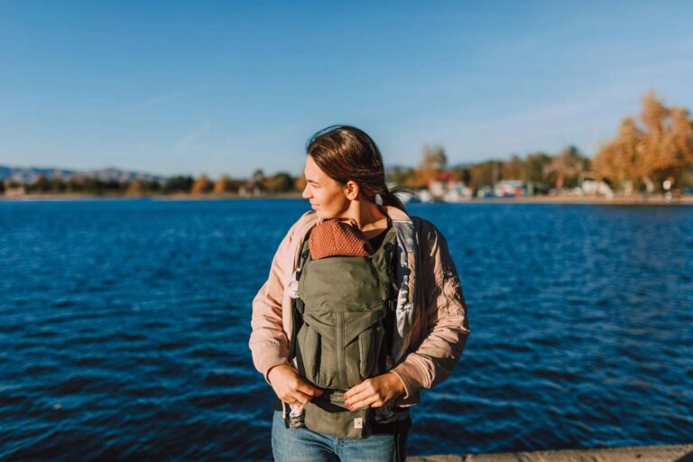 Mother carrying her newborn close in a front baby carrier outdoors