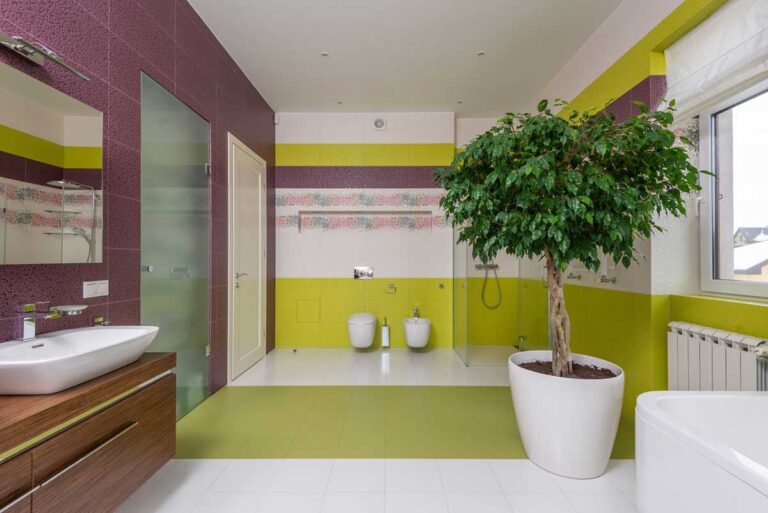 Bright bathroom with colorful walls, a ceramic sink, mirror, and a potted plant by the window