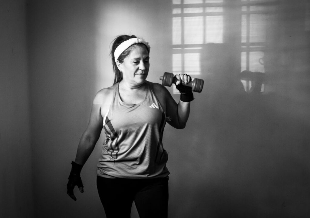 Woman exercising with a dumbbell at home in a black-and-white photograph